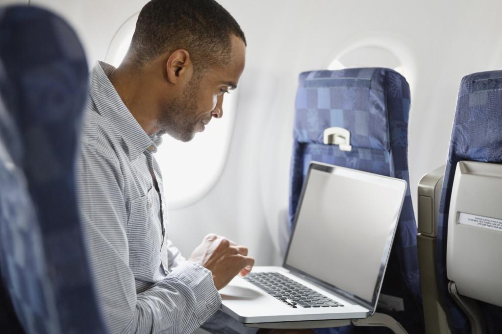 Man using laptop in airplane